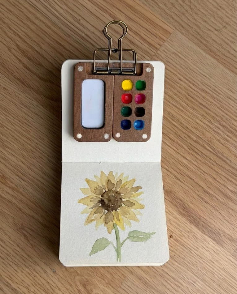 Tobio’s Kits sunflower watercolor painting, painted in a small watercolor sketchbook with soft washes and simple details.