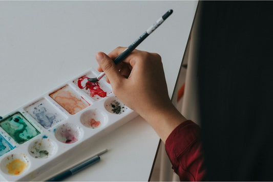 Person dipping a paintbrush on a palette