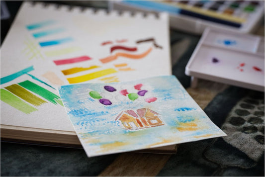Small watercolor painting of a house with balloons