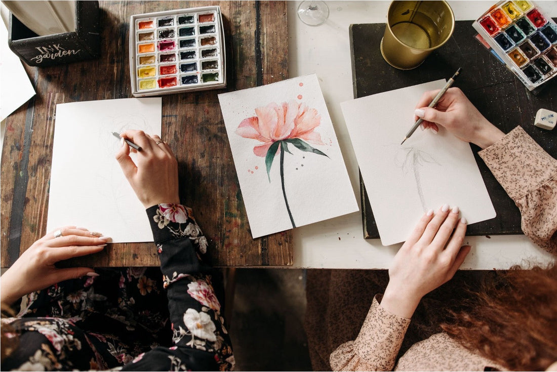 Two beginners using a watercolor kit to paint flowers
