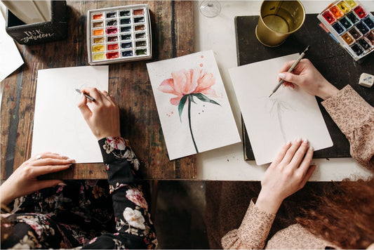 Two beginners using a watercolor kit to paint flowers