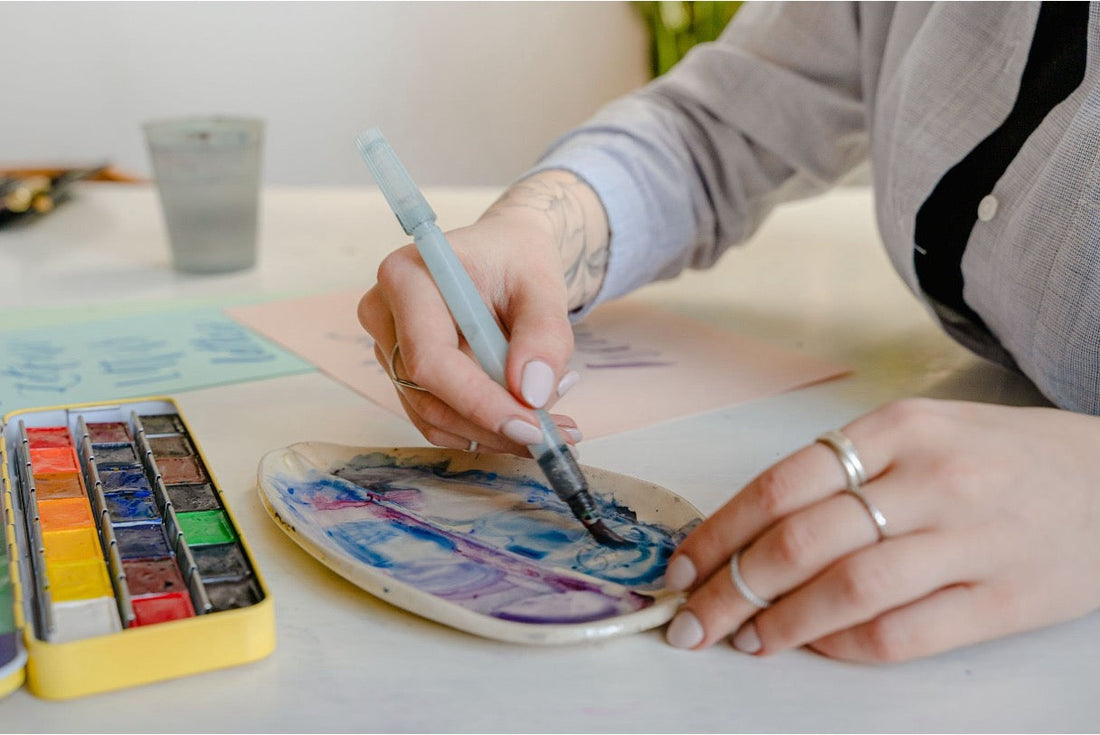 Woman holding a water brush as she does watercolor painting