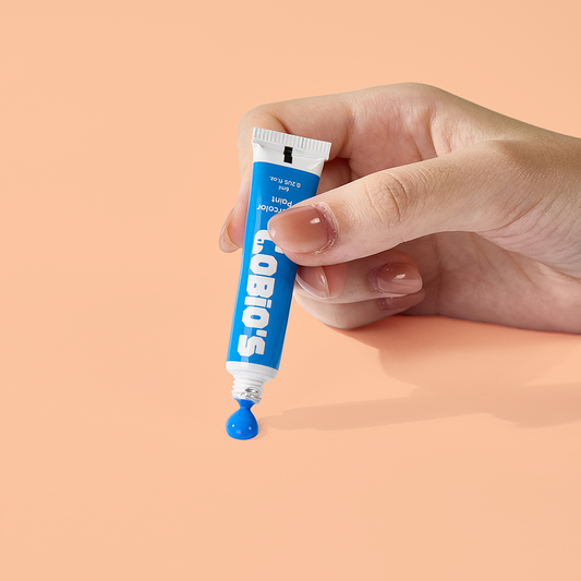 Person squeezing a blue paint tube from Tobio’s Kits