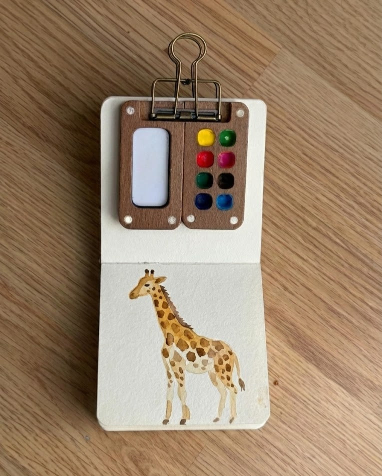 Tobio’s Kits giraffe watercolor painting, painted in a small watercolor sketchbook with soft washes and simple details.