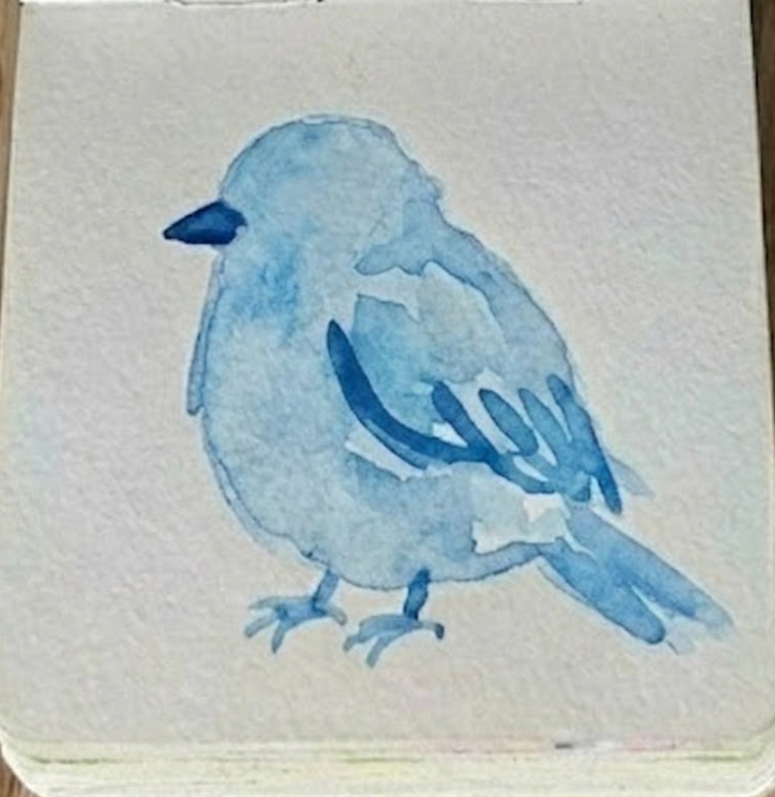 Dropping darker ultramarine blue feather details into a damp sketchbook bluebird watercolor painting.