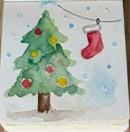 The finished christmas watercolor painting in a sketchbook, featuring black ink outlines, a hanging string, and blue snow splatters.