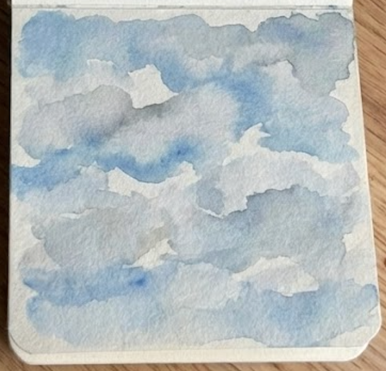 The final step of the loose cloud watercolor painting in a sketchbook, with dilute Payne's Gray shadows added to the bottom of the clouds for depth.