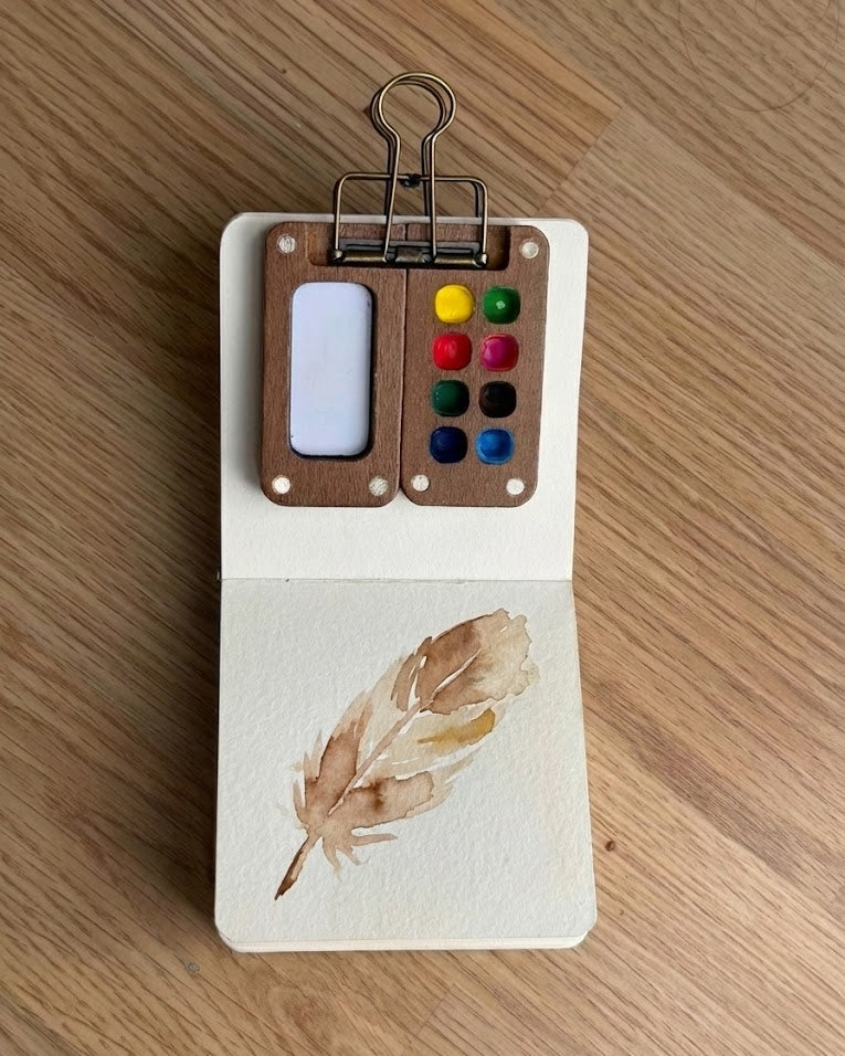 Tobio’s Kits feather watercolor painting, painted in a small watercolor sketchbook with soft washes.