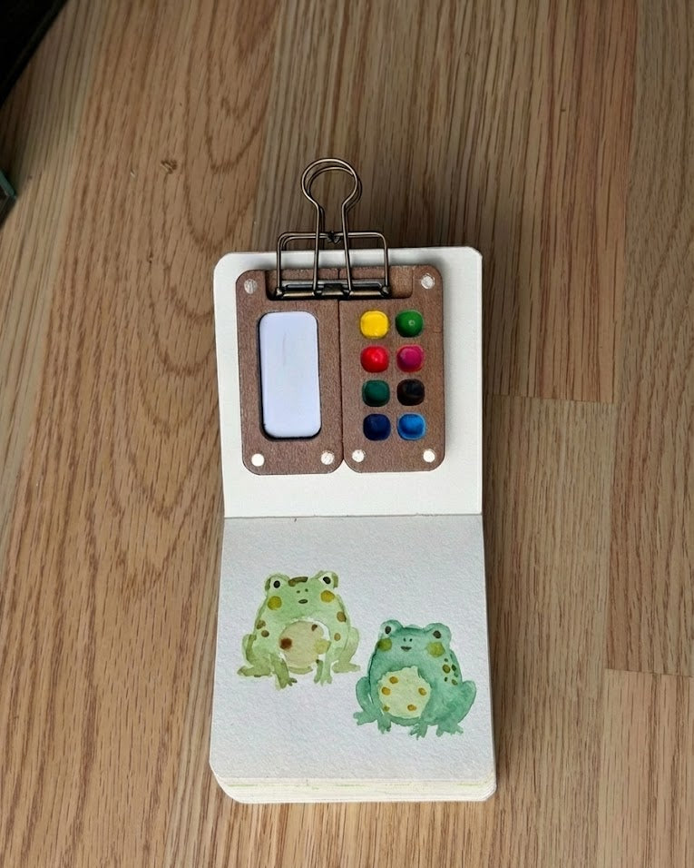 Tobio’s Kits watercolor painting of frogs, painted in a small watercolor sketchbook with soft washes and simple details.