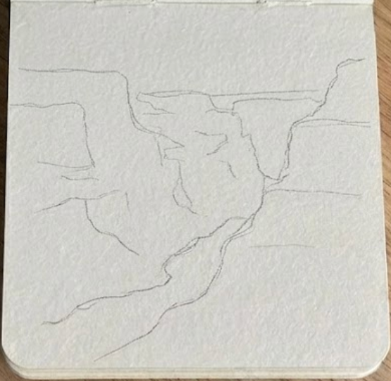 Pencil sketch in an open sketchbook, outlining the cliffs and river for a grand canyon watercolor painting.