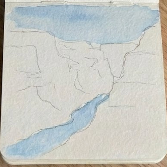 Initial stage of a grand canyon watercolor painting, with a light blue wash applied to the sky and river areas over the pencil outline.