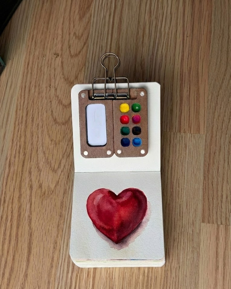 Tobio’s Kits heart watercolor painting, painted in a small watercolor sketchbook with soft washes and simple details.