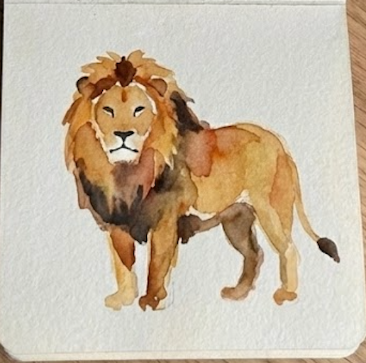 The finished lion watercolor painting inside a small open sketchbook with a mini wooden paint palette attached.