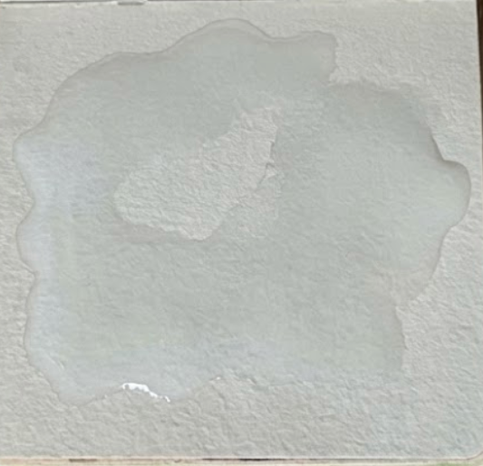 Water pooling on heavy-textured white art paper.