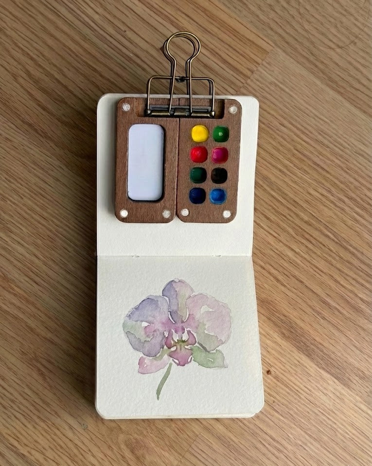 Tobio’s Kits orchid watercolor painting, painted in a small watercolor sketchbook with soft washes and simple details.