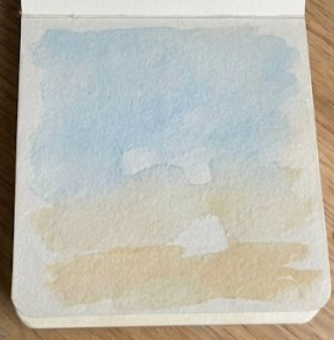 Initial sky and sand background wash in a sketchbook for a loose palm tree watercolor painting tutorial.