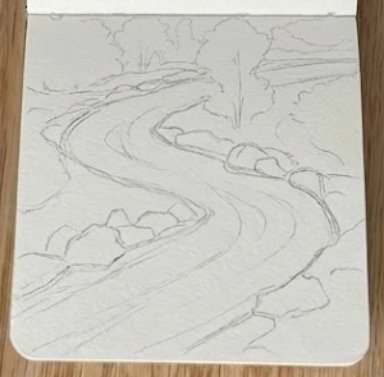 Initial pencil sketch of a winding river watercolor painting inside a small sketchbook resting on a wooden table.