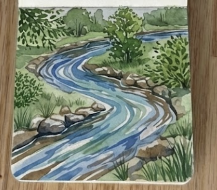 Blocking in green bushes and brown rocks along the banks of a river watercolor painting in progress.