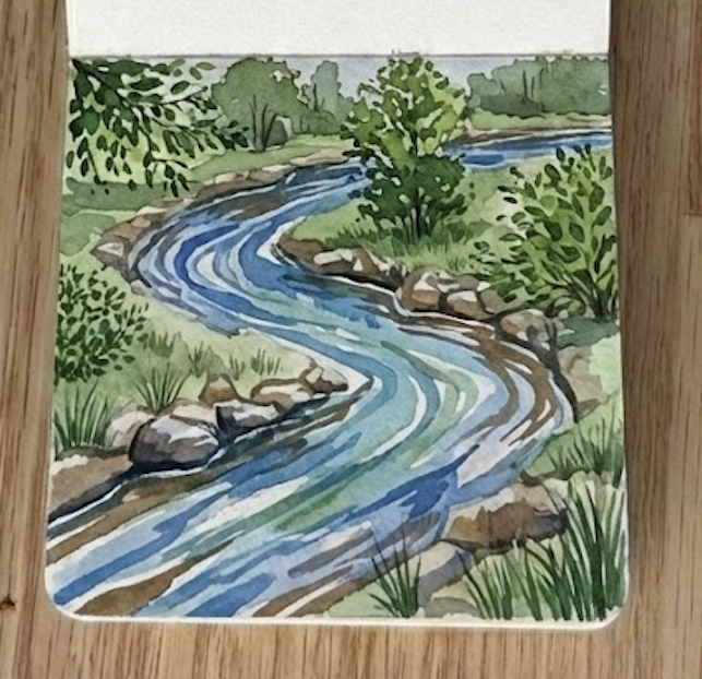 The completed river watercolor painting in an open sketchbook, featuring detailed green trees, shadows, and rippling water.