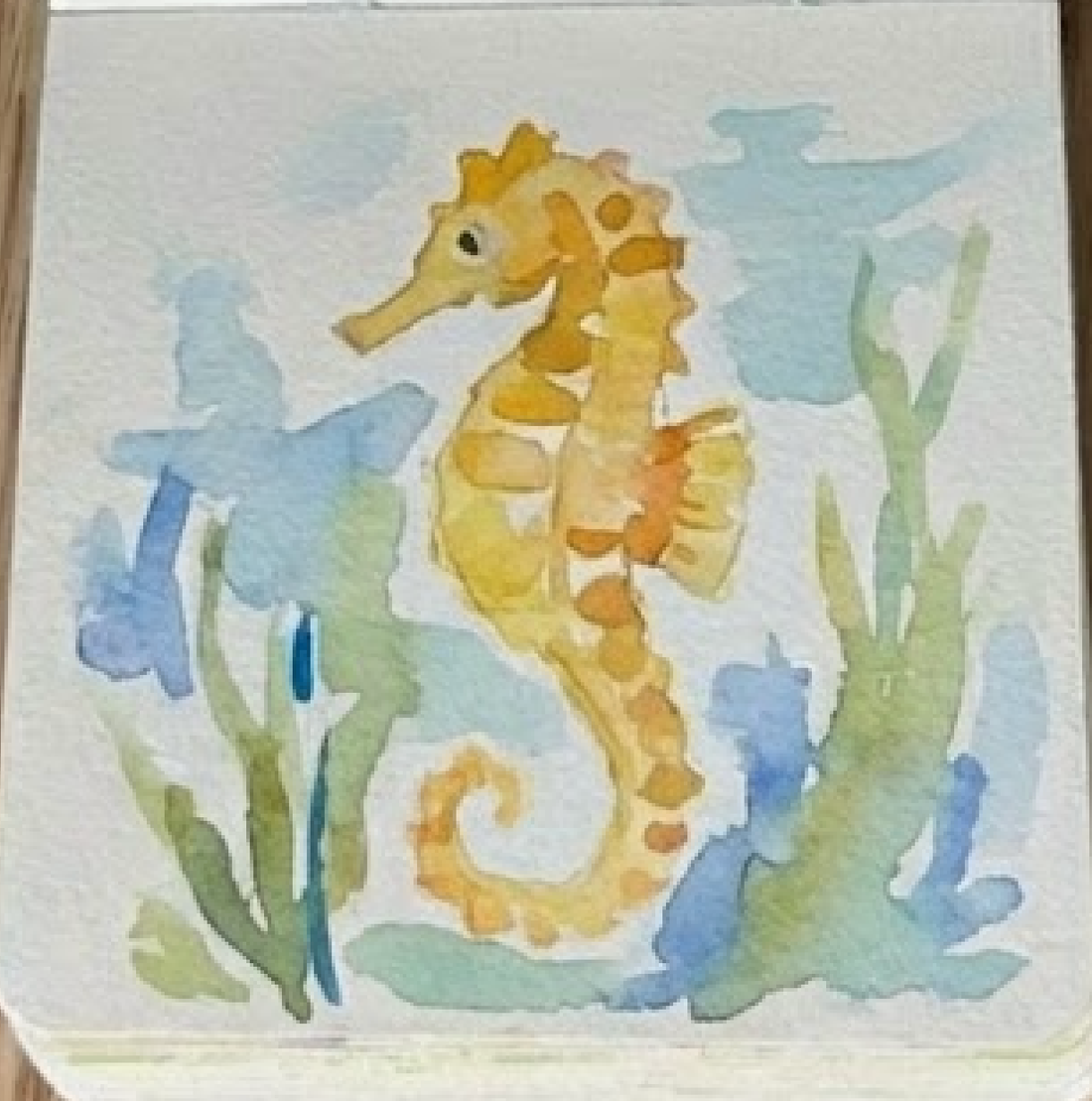 Completed loose style seahorse watercolor painting in a sketchbook showing final details like the dark eye and texture lines, step 4.