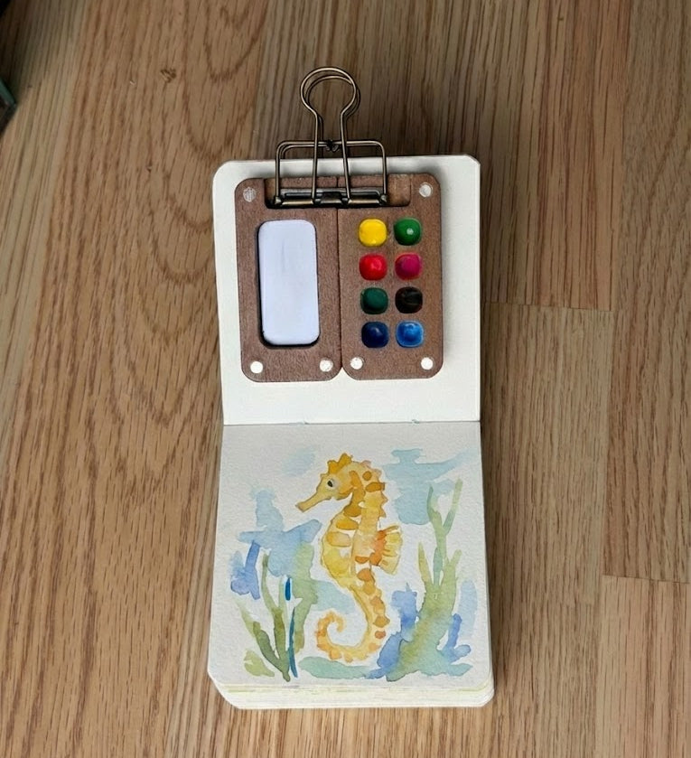 Finished watercolor seahorse with soft blue background and subtle salt texture