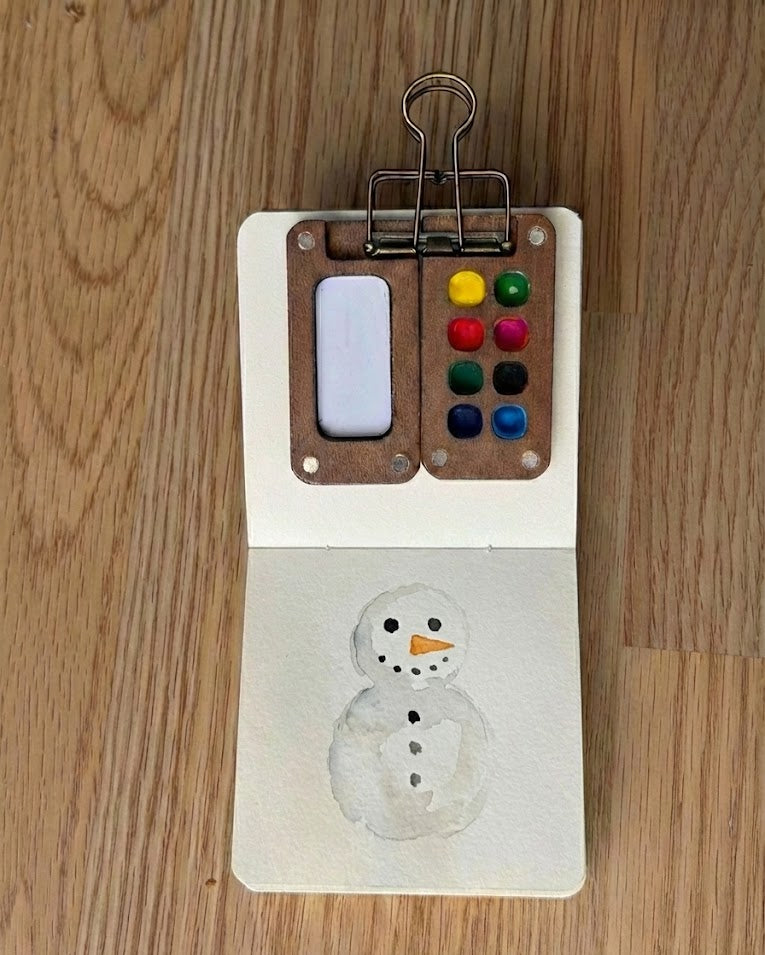 Tobio’s Kits snowman watercolor paintings, painted in a small watercolor sketchbook with soft washes and simple details.