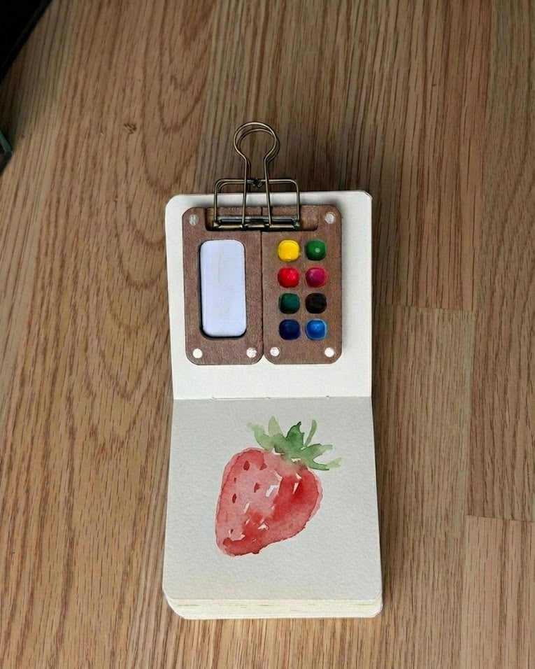Tobio’s Kits strawberry watercolor painting, painted in a small watercolor sketchbook with soft washes and simple details.