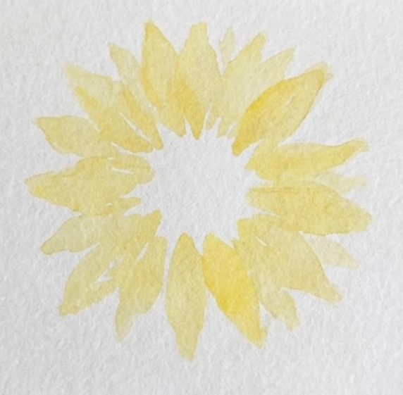 Step 1: The initial stage of a sunflower watercolor painting, showing loose, pale yellow brushstrokes forming a circle of radiating petals on textured white paper.