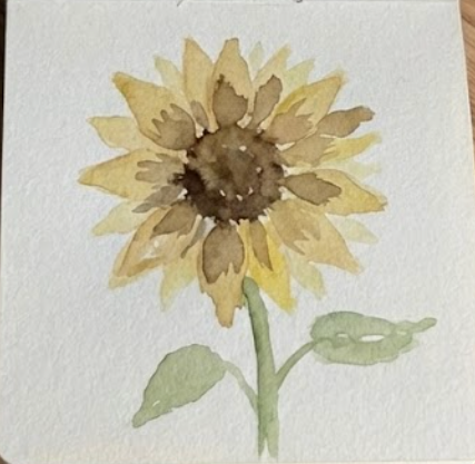 The completed expressive sketchbook style sunflower watercolor painting, featuring the finished yellow and brown flower head with an attached light green stem and two leaves.