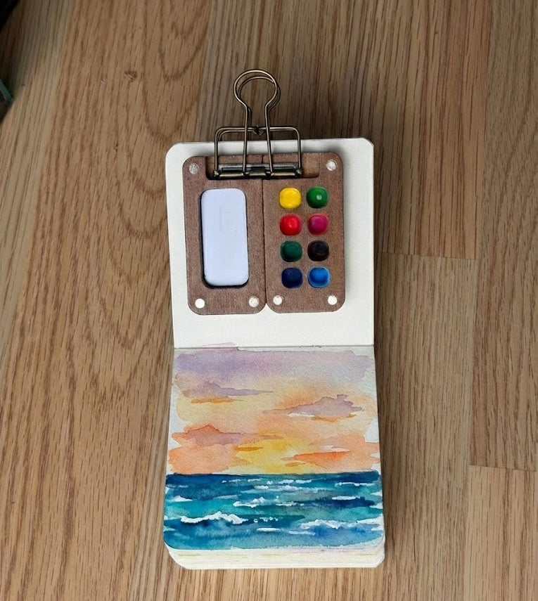Watercolor painting of a sunset in a sketchbook