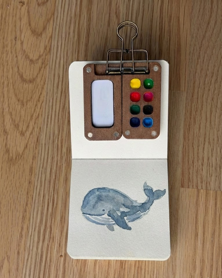 Tobio’s Kits whale watercolor painting, painted in a small watercolor sketchbook with soft washes and simple details.